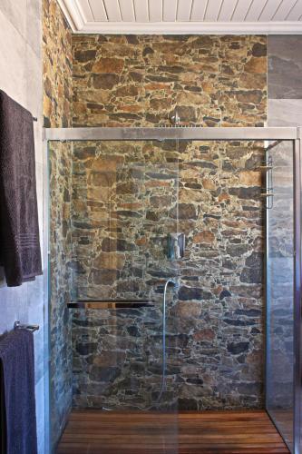 a bathroom with a glass shower with a stone wall at The Farm Life - Namibia in Helmeringhausen