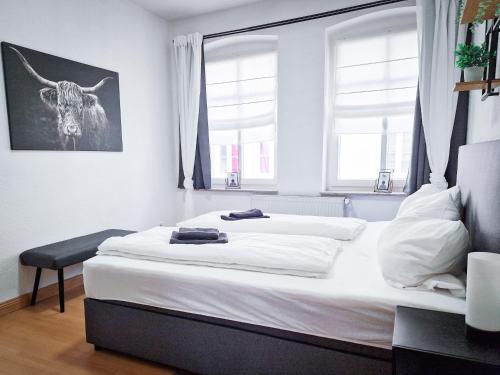 um quarto com uma grande cama branca e 2 janelas em großzügige Altstadtwohnung Lara für 6 Personen em Weißenfels