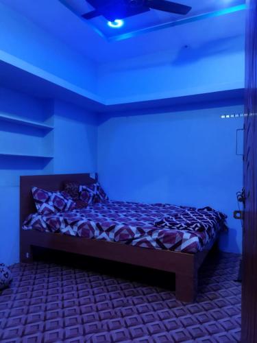 Cama en habitación con luz azul en Karthik home stay en Hampi