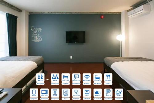 鹿児島市にあるROI SPACE 鹿児島のベッド2台と壁掛けテレビが備わる客室です。