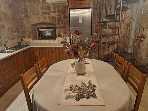 a dining room table with a vase of flowers on it at Villa Agia Sofia ένα υπέροχο καταφύγιο στο βουνό in Ayía Sofía