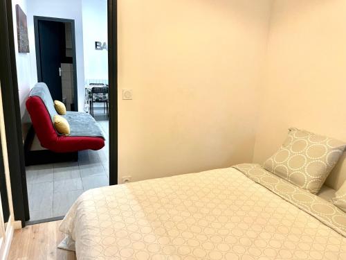 a bedroom with a bed and a red chair at La Sérénade Numéro 4 in Montreuil