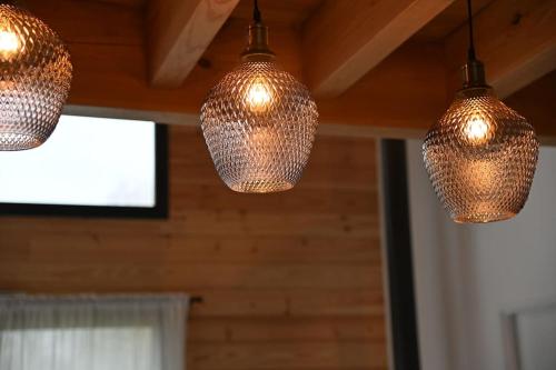three lights hanging from the ceiling of a room at Pinéa Lodge - Chalet Authentique en Pin des Landes in Saint-Yaguen