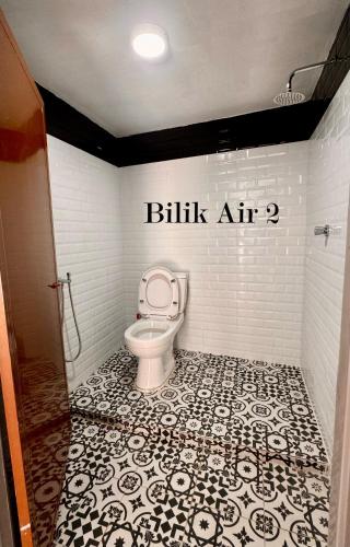 a bathroom with a toilet with a black and white tile floor at Bangli Homestay in Huma