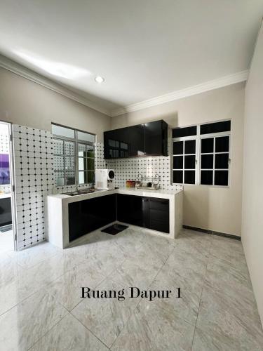a kitchen with black cabinets and a white counter top at Bangli Homestay in Huma