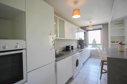 une cuisine blanche avec un évier et un lave-vaisselle dans l'établissement Apartment in residence with balcony and parking, à Lille