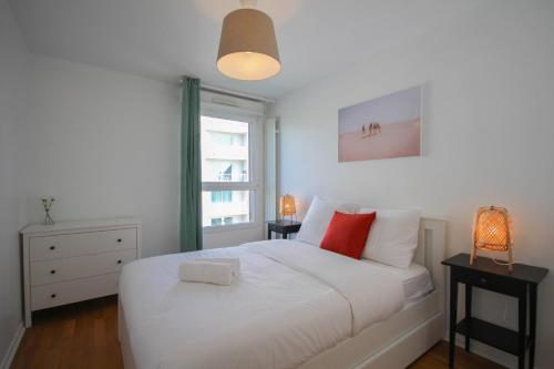 um quarto com uma cama branca e almofadas vermelhas em Apartment in residence with balcony and parking em Lille