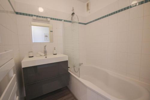 uma casa de banho branca com um lavatório e uma banheira em Apartment in residence with balcony and parking em Lille