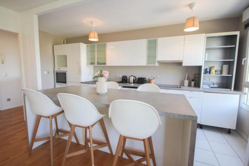 une cuisine avec des placards blancs et une grande île avec des chaises blanches dans l'établissement Apartment in residence with balcony and parking, à Lille