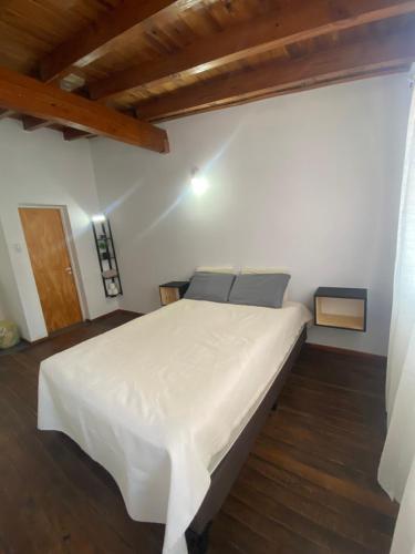 uma grande cama branca num quarto com pisos em madeira em Hermoso Dúplex para 4 personas em Las Heras