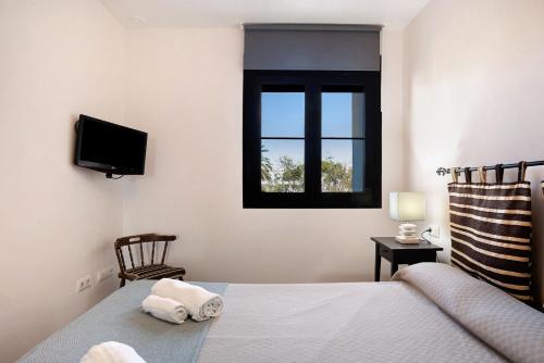 een slaapkamer met een bed, een tv en een raam bij Apartamento Coto 109 in Chiclana de la Frontera