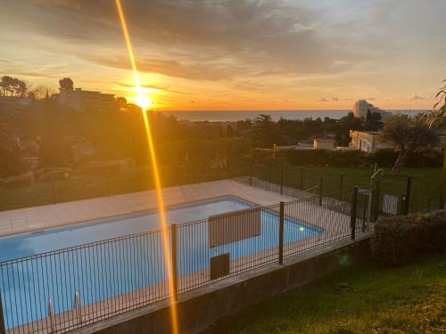 a swimming pool with the sunset in the background at Suite romantique SPICY LOVE - proche Nice et Cannes - Jacuzzi privatif - French Riviera - luxe in Villeneuve-Loubet