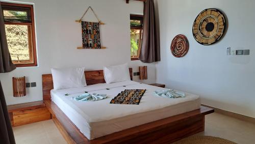 1 dormitorio con 1 cama con reloj en la pared en Aluna Beach Apartments, en Nungwi