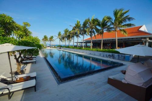 a swimming pool in front of a resort with palm trees at Luxury Beach Resort Da Nang in Da Nang