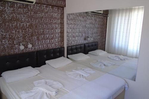 un grande letto bianco con sopra asciugamani di TOROS OTEL DİDİM a Didim