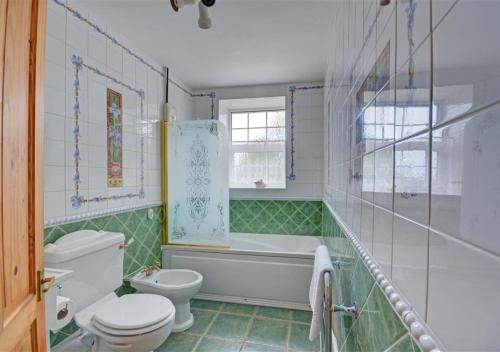 a bathroom with a tub and a toilet and a sink at Manor Cottage in Redruth