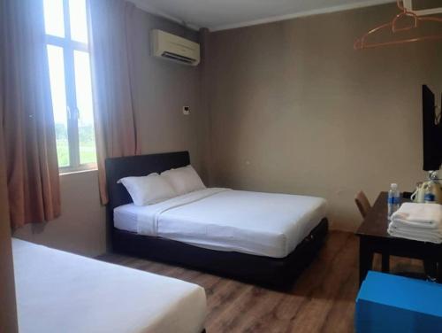 een hotelkamer met 2 bedden en een raam bij M BOUTIQUE INN (PERMYJAYA) in Miri