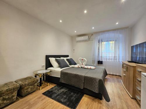a bedroom with a bed and a couch and a television at Centar RI-ROOM in Rijeka