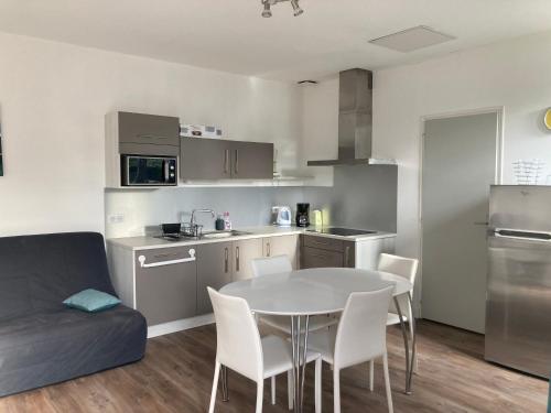 - une cuisine avec une table et un canapé dans une chambre dans l'établissement Maisonnette au calme prôche forêt et bord de mer, à Saint-Jean-de-Monts