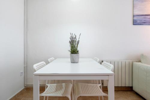 a white table with two chairs and a potted plant at Center Beach Calafell in Calafell
