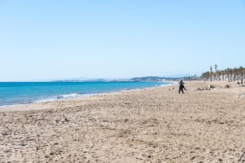 a person walking on a sandy beach near the ocean at Center Beach Calafell in Calafell
