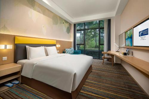 a hotel room with a bed and a flat screen tv at Holiday Inn Express Emei Mountain by IHG in Emeishan