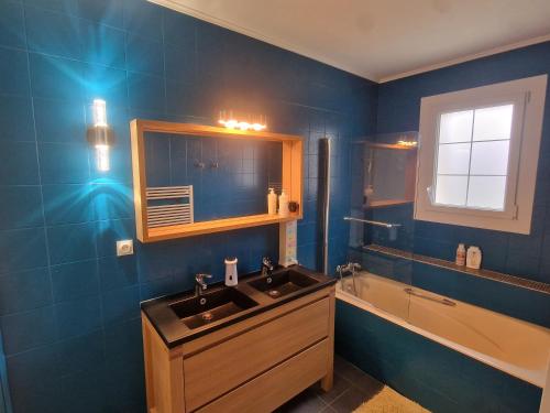 ein blaues Badezimmer mit einem Waschbecken und einer Badewanne in der Unterkunft LUCIE LEBRETON in Versainville