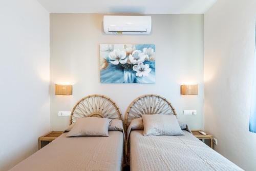 2 camas en un dormitorio con una pintura en la pared en Villa Terra en Son Bou