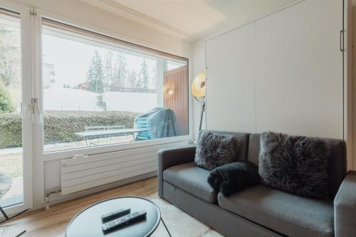a living room with a couch and a large window at Studio rénové et élégant en plein centre in Crans-Montana