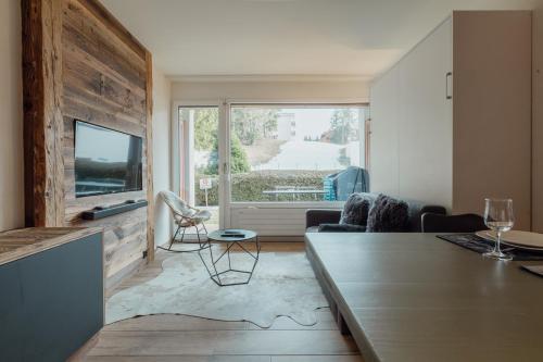 a living room with a couch and a tv at Studio rénové et élégant en plein centre in Crans-Montana