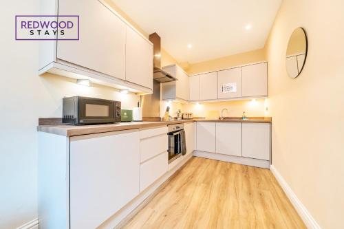 a kitchen with white cabinets and a microwave at Festival Place, Town Center Serviced Apartments, Perfect of Contractors & Families FREE Wifi & Netflix By REDWOOD STAYS in Basingstoke