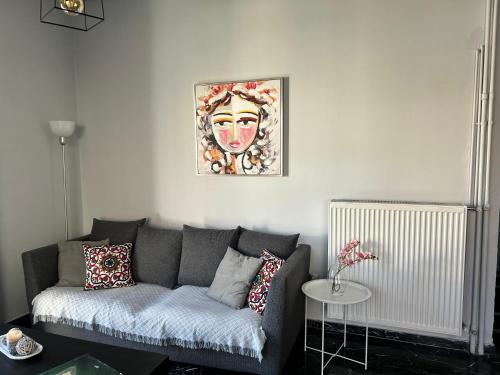 a living room with a gray couch and a painting on the wall at Beautiful apartment next to metro station in Athens