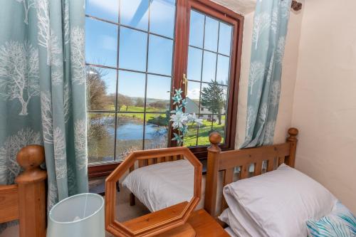 a bedroom with two beds and a window at Lakeside Cottage in Woolacombe
