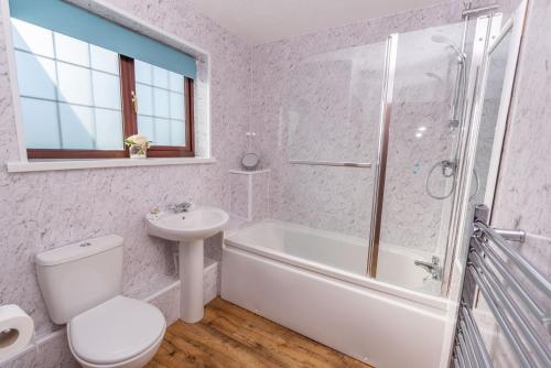 a white bathroom with a toilet and a sink at Lakeside Cottage in Woolacombe