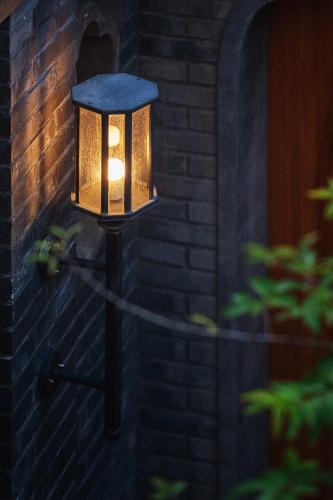 a light on the side of a brick wall at Beijing Le Zai Nan Luo Gu Xiang Wang Fu Jing Forbidden City Courtyard Hotel&Free laundry service&Free coffee &Paid Dumpling experience service in Beijing