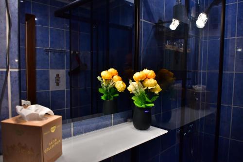 Comfortable 4-Room Apartments in Jekabpils في جيكاببيلس: حمام من البلاط الأزرق مع مزهرين من الزهور على رف
