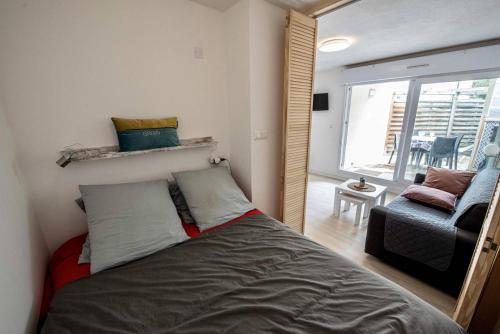 um quarto com uma cama, uma cadeira e uma janela em Residence du Centre Joli studio rénové avec coin nuit terrasse et parking privé em Capbreton