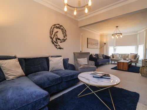 a living room with a blue couch and a table at First Light in Lowestoft