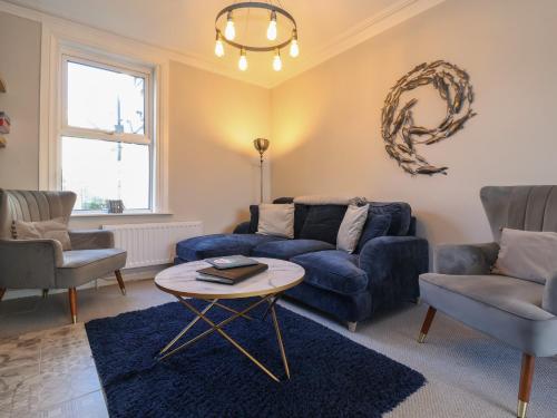 a living room with a blue couch and chairs at First Light in Lowestoft