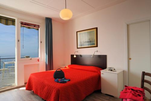 a bedroom with a red bed with a red blanket at Hotel Tirreno in Alassio