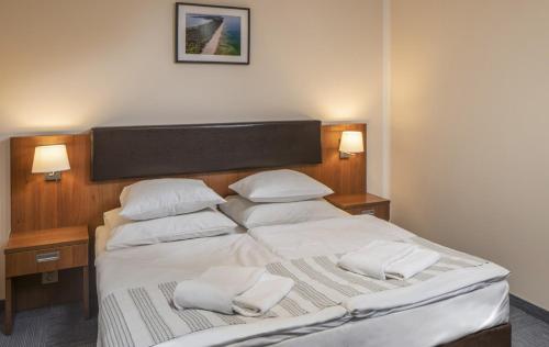 a bedroom with a large bed with white sheets and pillows at Maximus Spa in Dziwnówek
