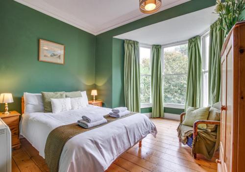 a bedroom with a bed with green walls and a window at Boslandew House in Paul