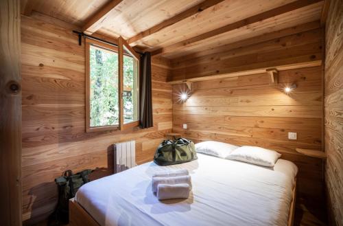 a bedroom with a bed in a wooden cabin at Huttopia Lac de Rillé in Rillé