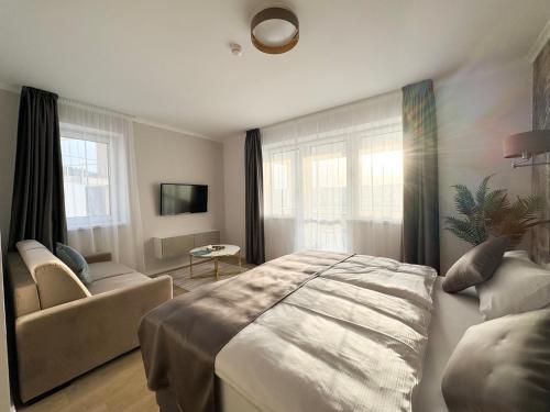 a bedroom with a bed and a couch and windows at Salt Hill Premium Apartments in Egerszalók