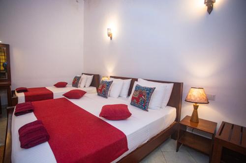 two beds in a room with red and white at 209 Nooit Gedacht in Unawatuna