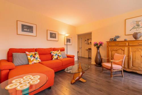 un salon avec un canapé orange et une table dans l'établissement 2 BR apartment with parking, 5 minutes from Lille, à Marcq-en-Barœul