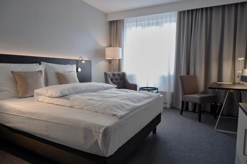ミンデンにあるLindgart Hotel Mindenの大きなベッドとデスクが備わるホテルルームです。