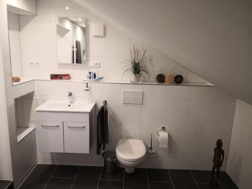 a white bathroom with a sink and a toilet at Über den Dächern von Mörfelden-Walldorf in Mörfelden-Walldorf