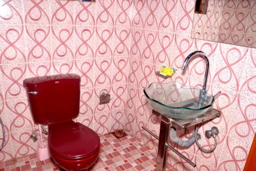 a bathroom with a red toilet and a sink at The Kings Villa. in Wattala