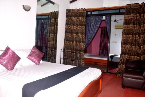 a bedroom with a bed with curtains and a chair at The Kings Villa. in Wattala